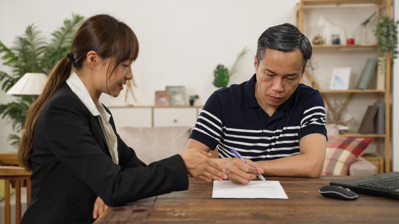A man reviewing and signing legal documents with a professional, illustrating discussions related to a grant of probate in Singapore.