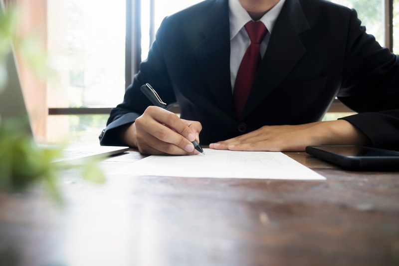 A professional signing legal documents at a desk, representing the Grant of Probate process in Singapore.